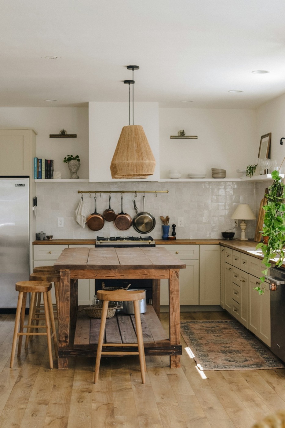A kitchen with open shelves, copper pans and a wooden island