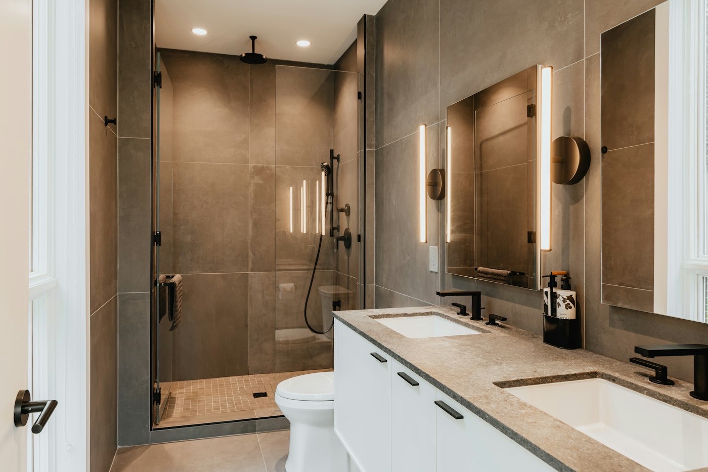 A bathroom with a walk-in shower, stone-look tile and a long vanity