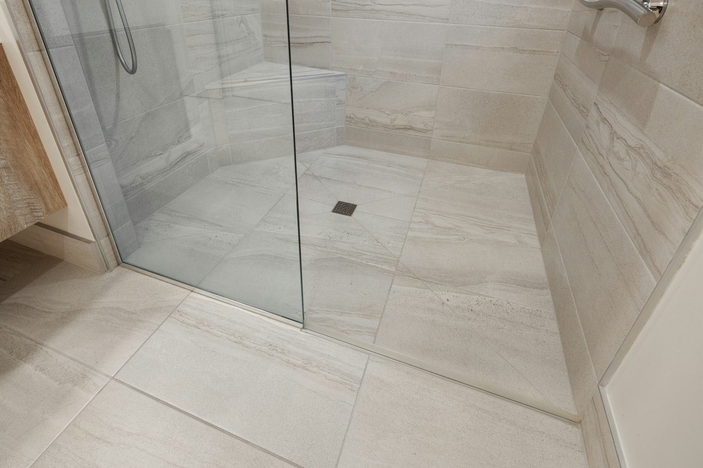 A large-format tiled shower floor with a linear drain
