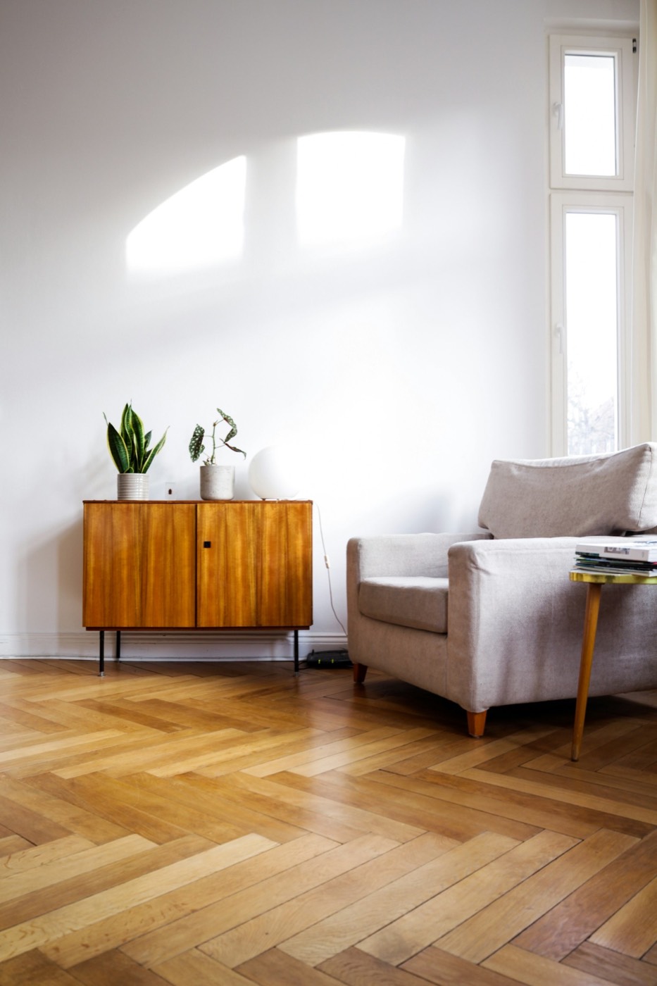 A living room with a mid-century sideboard on a pale wood floor